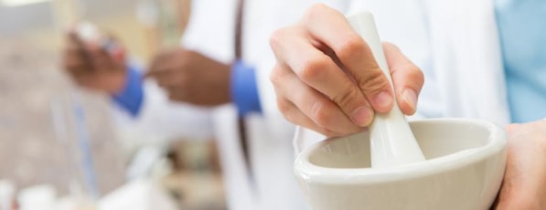 A hand holding a mortar and pestle